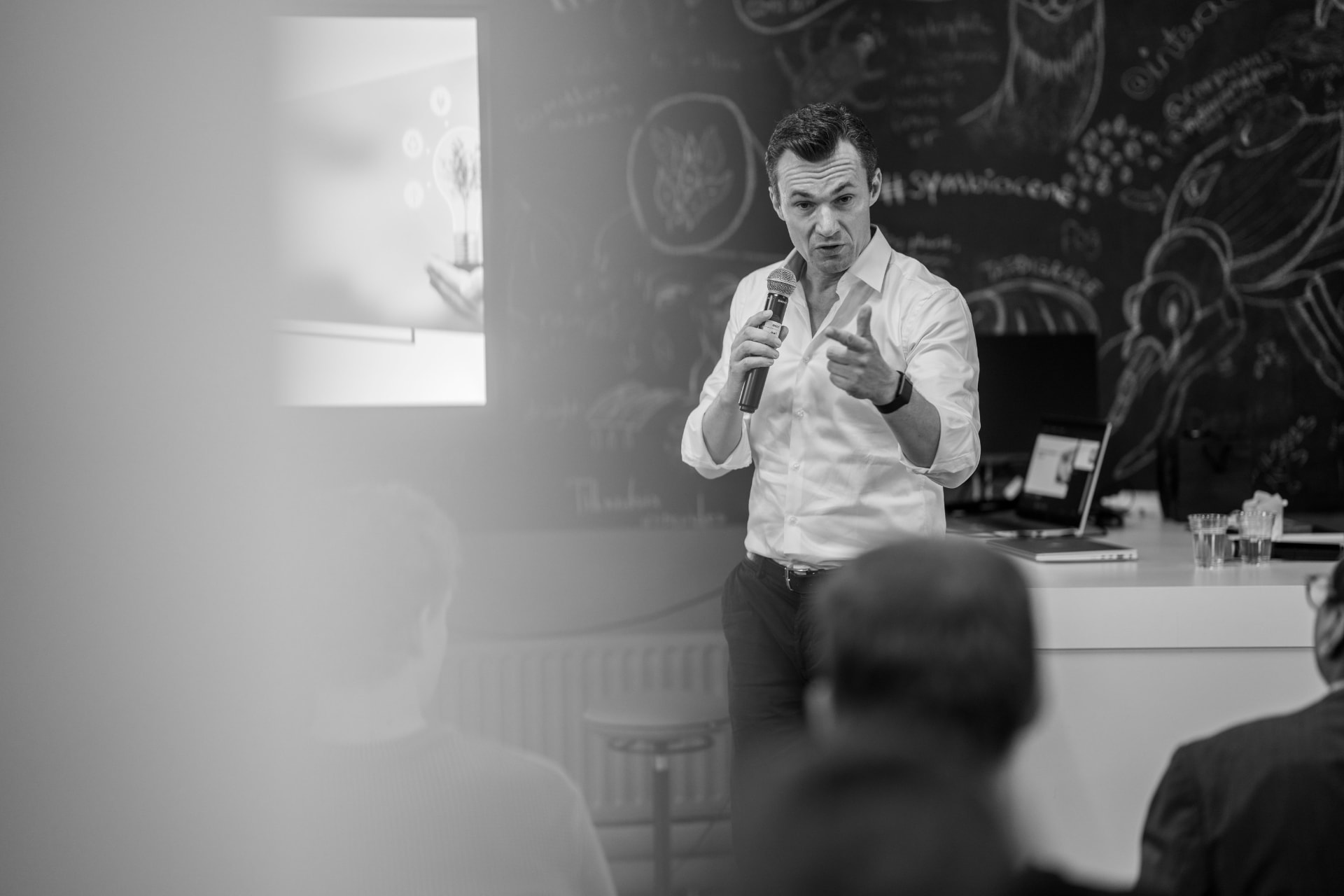 René Bohnsack speaking to an audience in front of a chalkboard wall